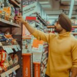woman in yellow sweater holding red and white box